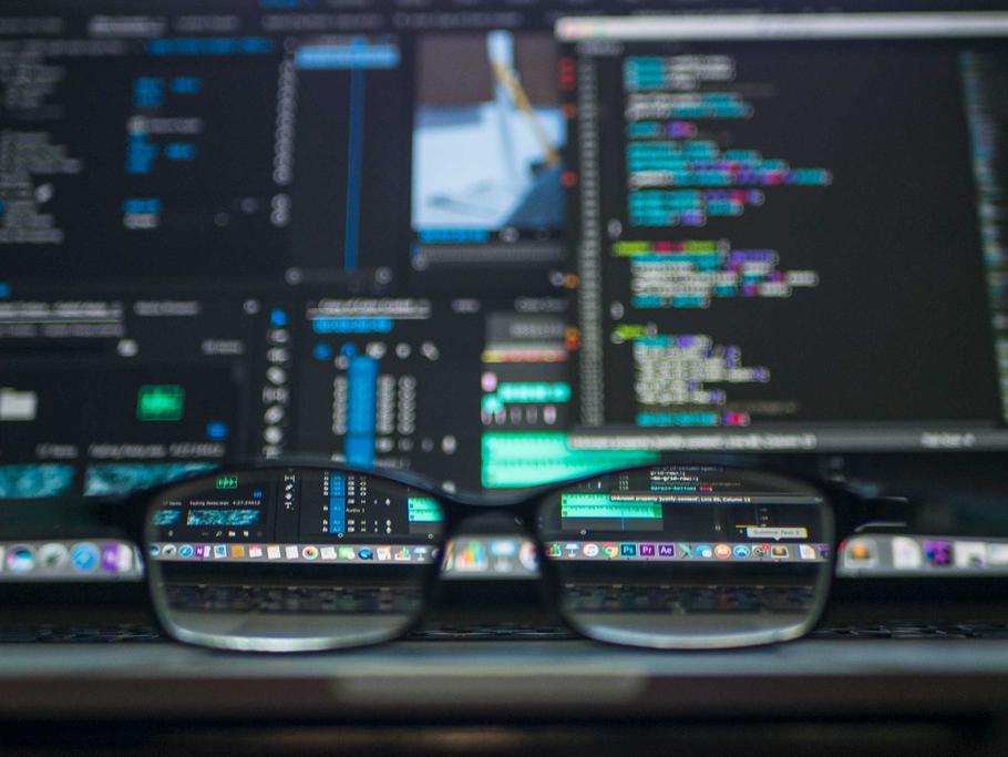 Image of code on a computer with glasses in front